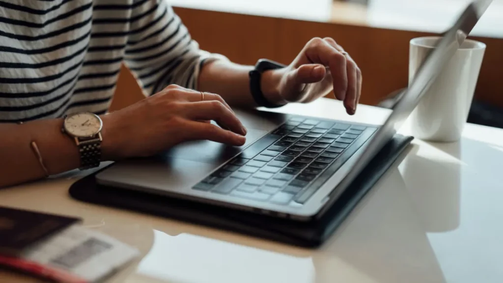 Person seated at the table using laptop learning how to implement pay transparency: a tactical guide